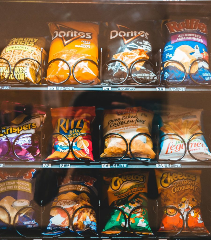 Snack vending machine stocked with popular branded snacks, healthy options and protein bars in a workplace.