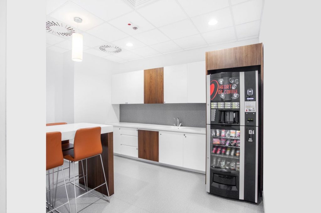 Energy-efficient snack vending machine with LED lighting in a modern commercial workplace.