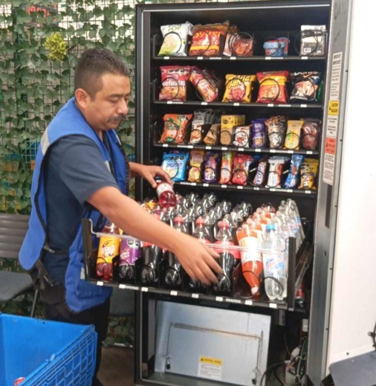 Technician installing a modern snack, drinks and coffee vending machine in a commercial workplace.