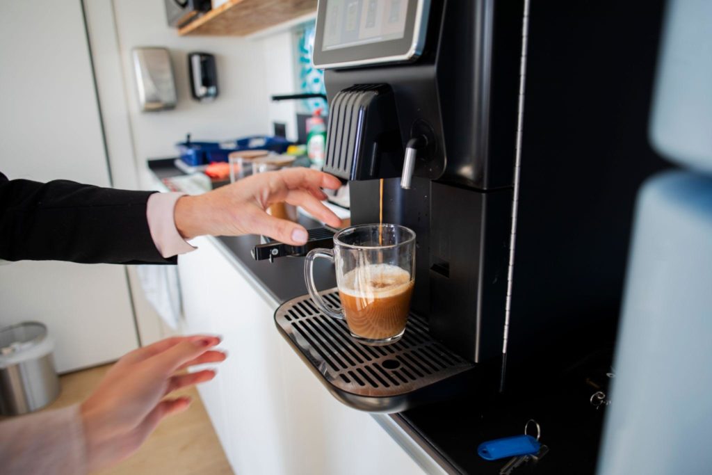 Bean-to-cup coffee machine preparing a fresh barista-style coffee in a modern office break room.